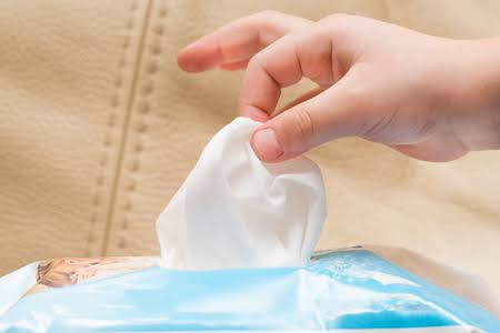 Hand pulling a premium non-woven dry wipe from a soft pack